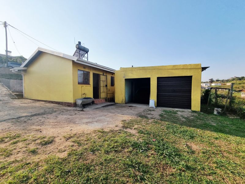 Rear view of a yellow painted house featuring a garage with a roller shutter door and a roof-mounted solar water heater.