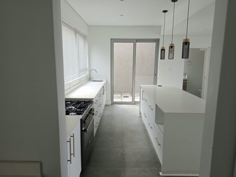 Modern kitchen featuring a central island, gas stove, stone countertops, and direct access to a rear patio area through sliding glass doors.