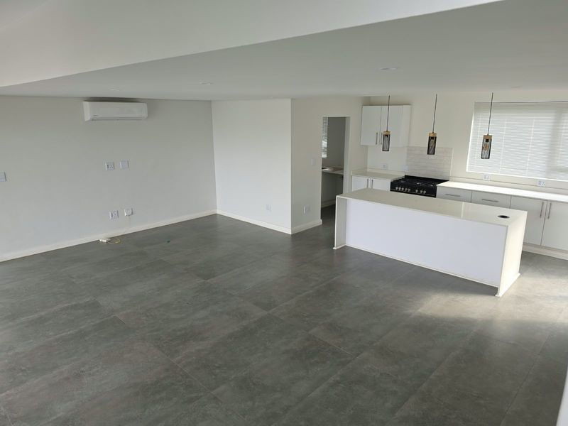 Spacious open-plan living and kitchen area featuring modern tiled floors, a central island, and a built-in gas stove, perfect for contemporary living.
