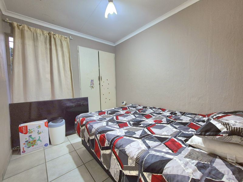 A functional bedroom featuring tiled flooring, a built-in wardrobe, and neutral wall finishes, offering a practical space for rest.