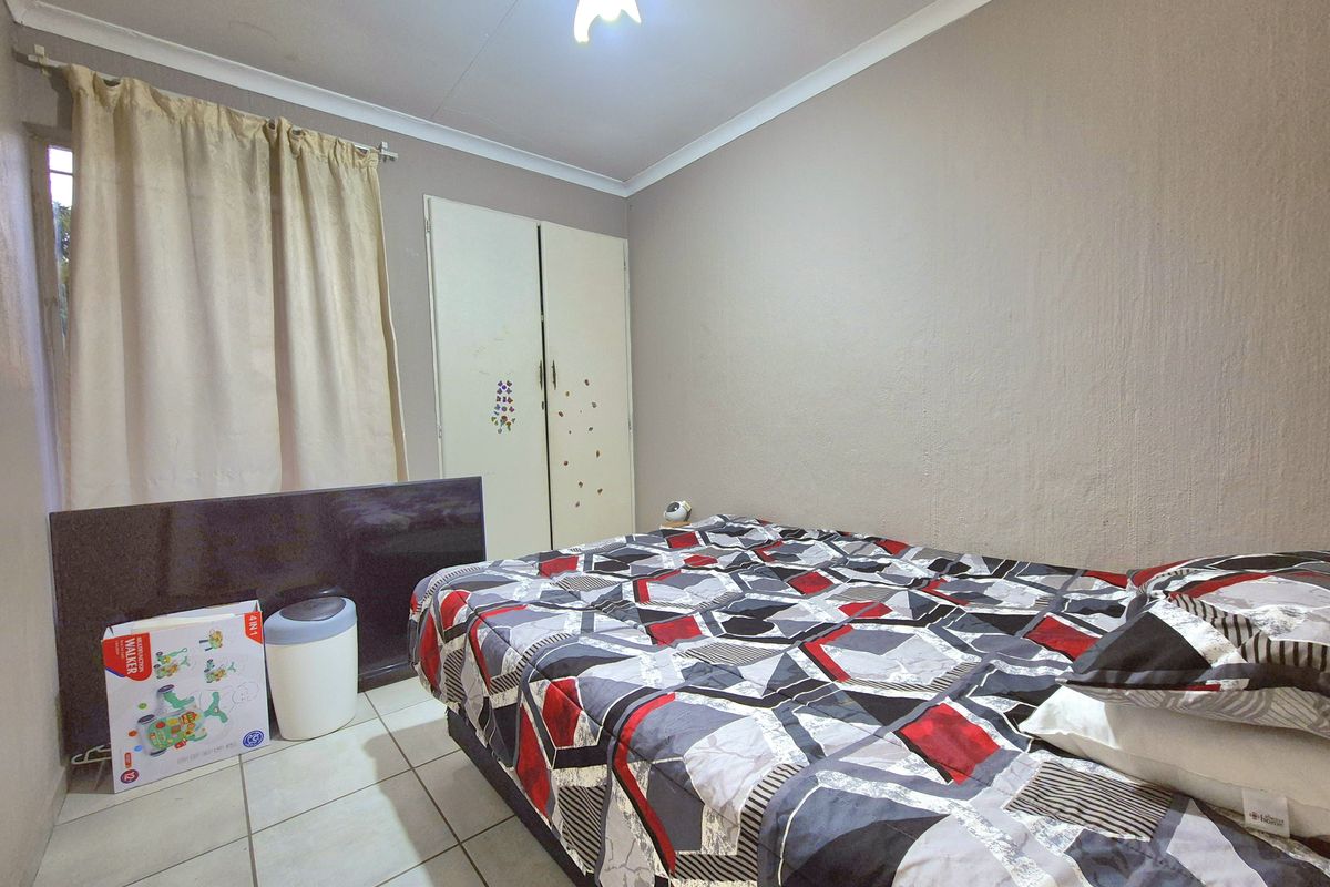 A functional bedroom featuring tiled flooring, a built-in wardrobe, and neutral wall finishes, offering a practical space for rest.