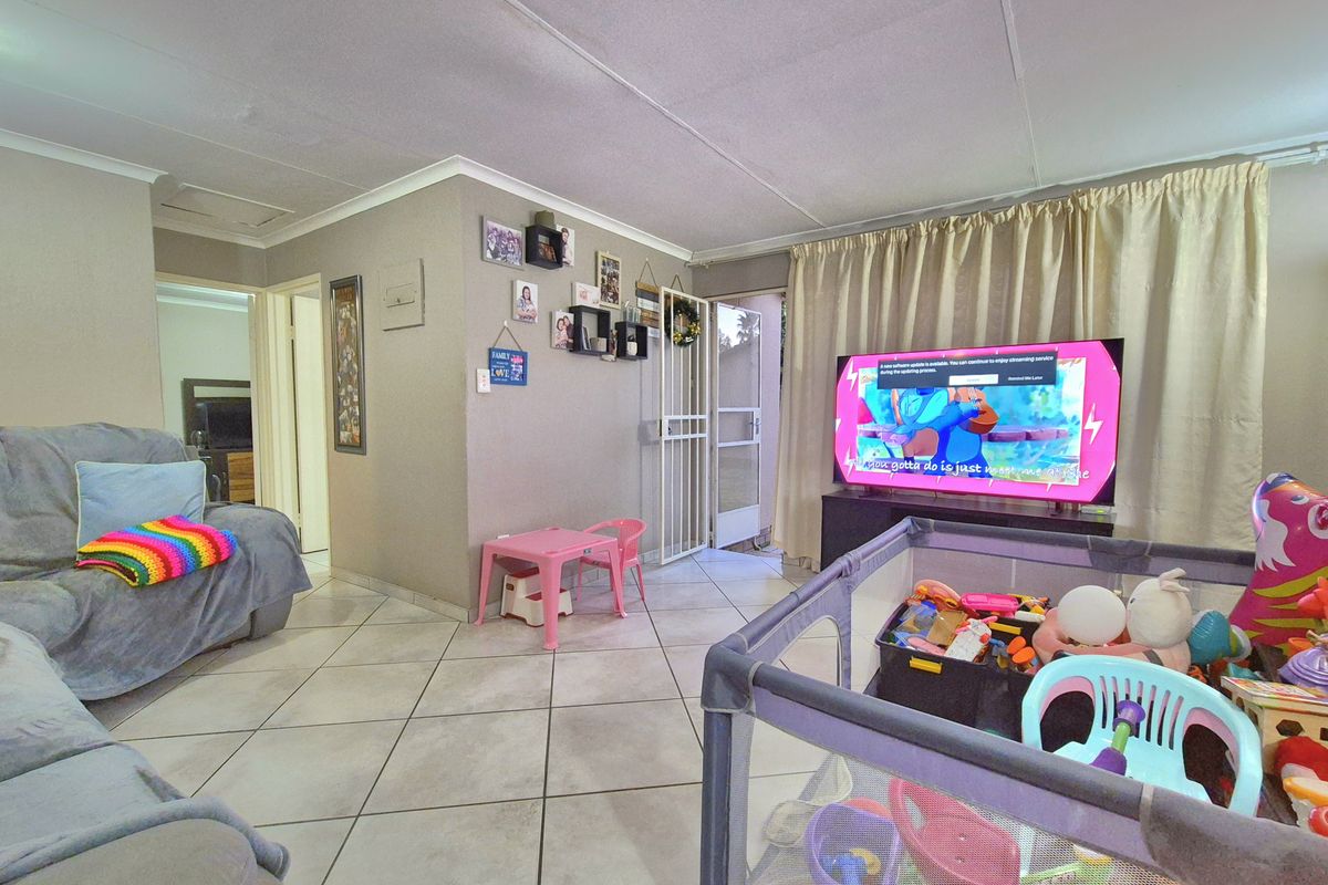 A functional living room featuring tiled flooring and a security gate, providing access to the exterior.