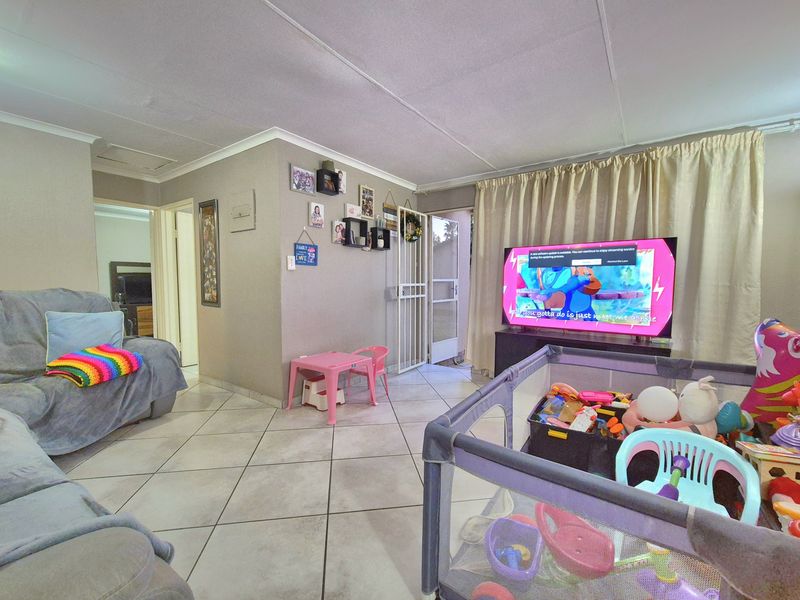 A functional living room featuring tiled flooring and a security gate, providing access to the exterior.