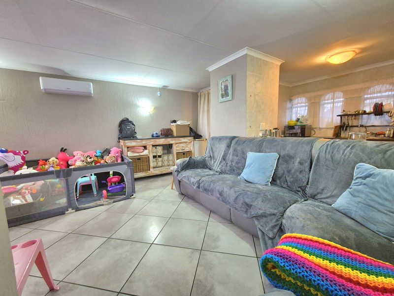 Open plan living area featuring tiled flooring, a split-system air conditioner, and a central tiled pillar, offering a functional layout for daily living.