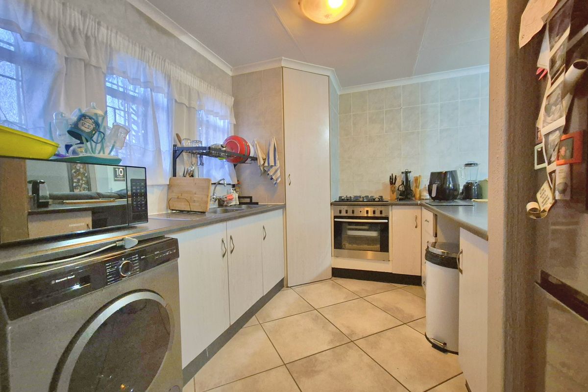 Functional kitchen featuring built-in cabinetry, gas hob, oven, extractor fan, and tiled finishes, providing a practical workspace for daily cooking needs.