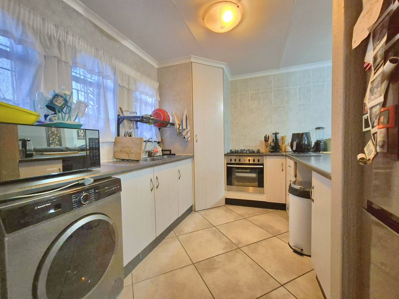 Functional kitchen featuring built-in cabinetry, gas hob, oven, extractor fan, and tiled finishes, providing a practical workspace for daily cooking needs.