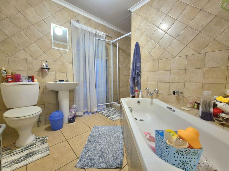 A functional bathroom featuring a pedestal basin, bathtub, and separate shower enclosure with full-height ceramic wall tiling.