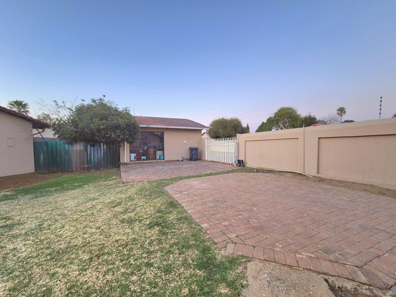 Rear garden area featuring a paved patio, perimeter walling, and a small lawn space.
