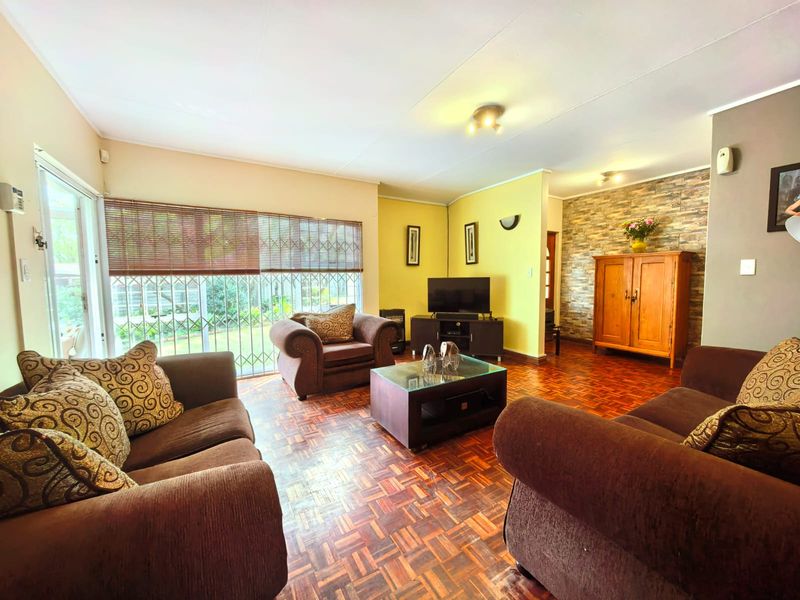 Spacious living room featuring warm parquet flooring, a textured stone veneer feature wall, and large sliding doors providing access to the garden.
