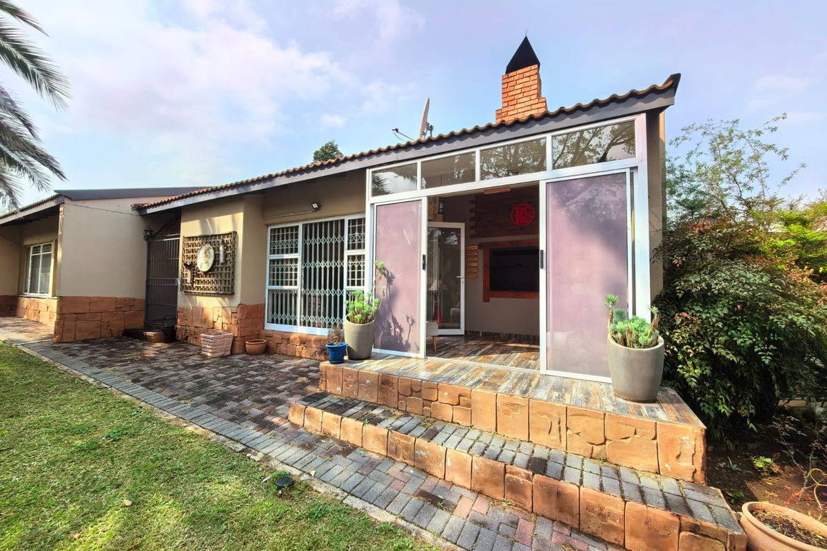 Rear exterior view featuring a paved patio, brick chimney, and sliding glass doors leading into the home.
