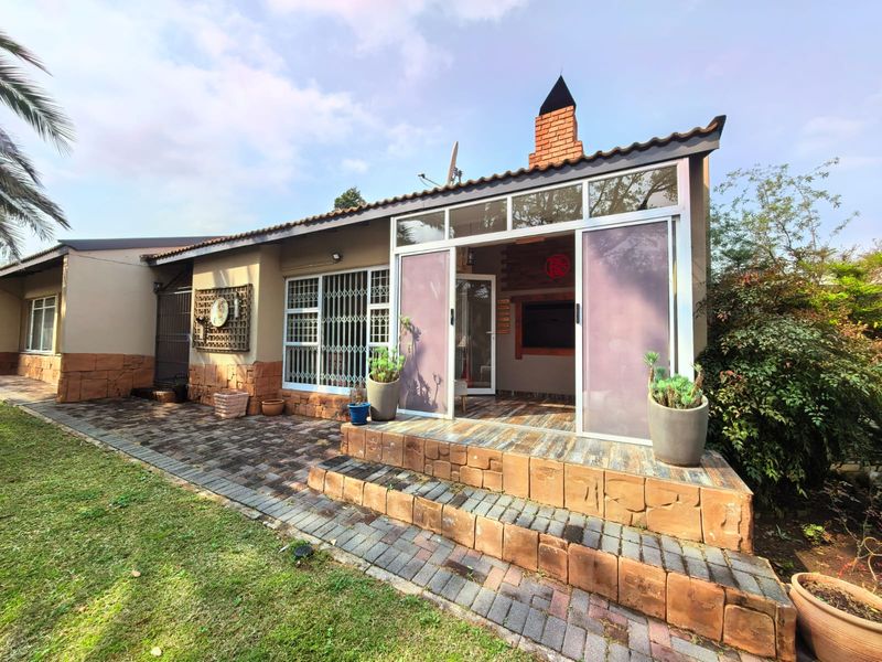Rear exterior view featuring a paved patio, brick chimney, and sliding glass doors leading into the home.
