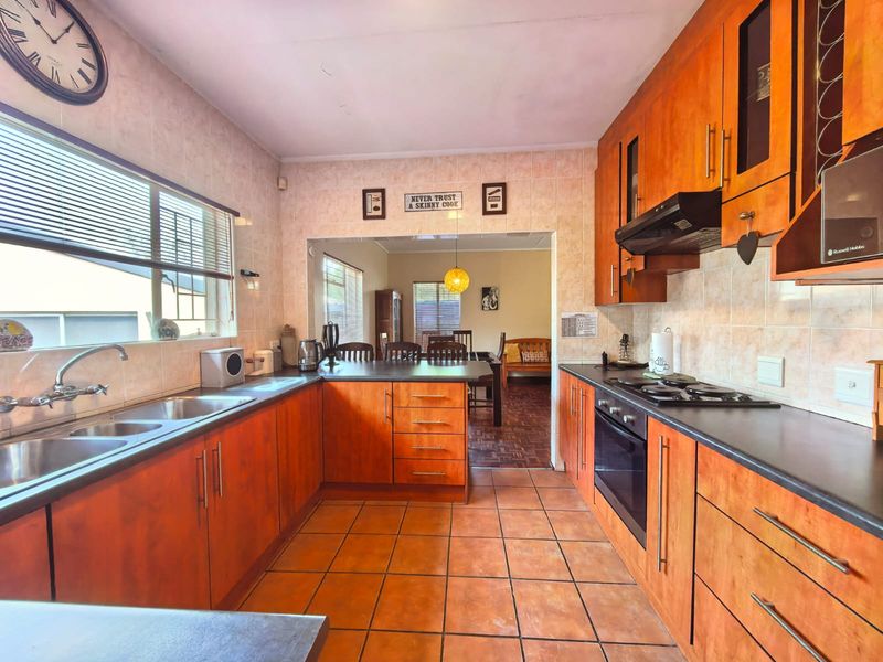 Functional kitchen featuring wooden cabinetry, laminate countertops, built-in oven, gas hob, and tiled flooring, with an open-plan flow to the dining area.