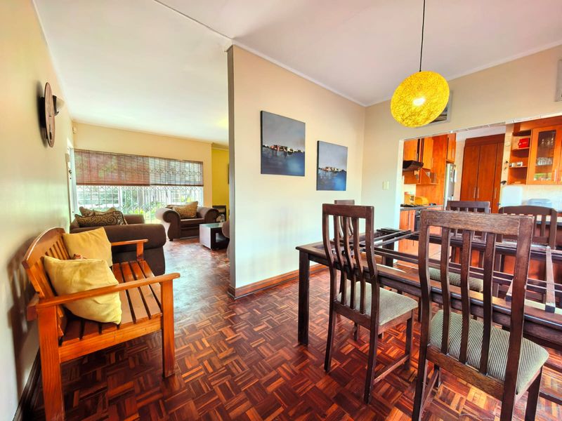 Open plan living and dining area featuring traditional parquet flooring, neutral walls, and a view into the adjacent kitchen space.