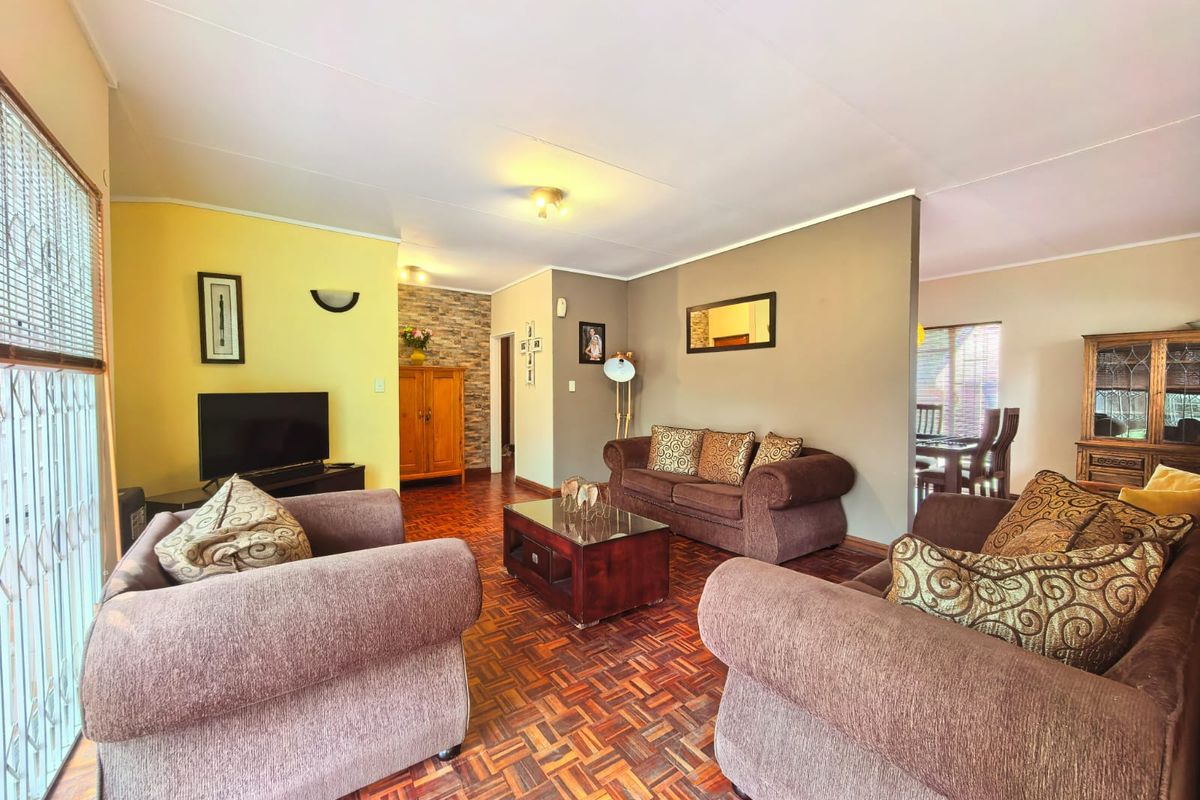 Spacious living room featuring classic parquet flooring, a decorative stone feature wall, and an open-plan layout connecting to the dining area.