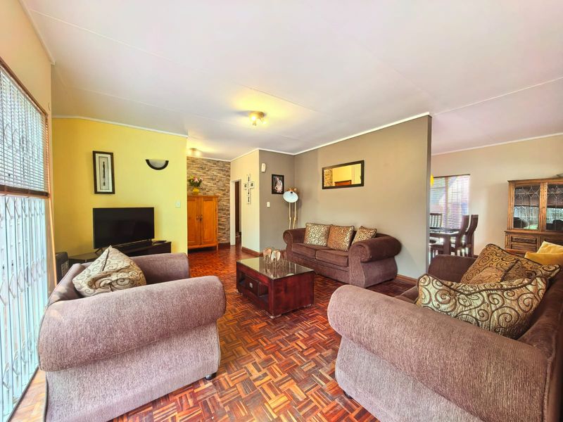 Spacious living room featuring classic parquet flooring, a decorative stone feature wall, and an open-plan layout connecting to the dining area.