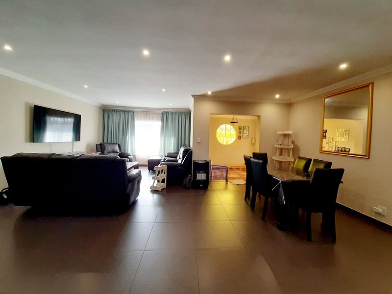 Spacious open-plan living and dining area featuring tiled flooring, recessed downlighting, and a neutral color palette, providing a versatile layout for family living.