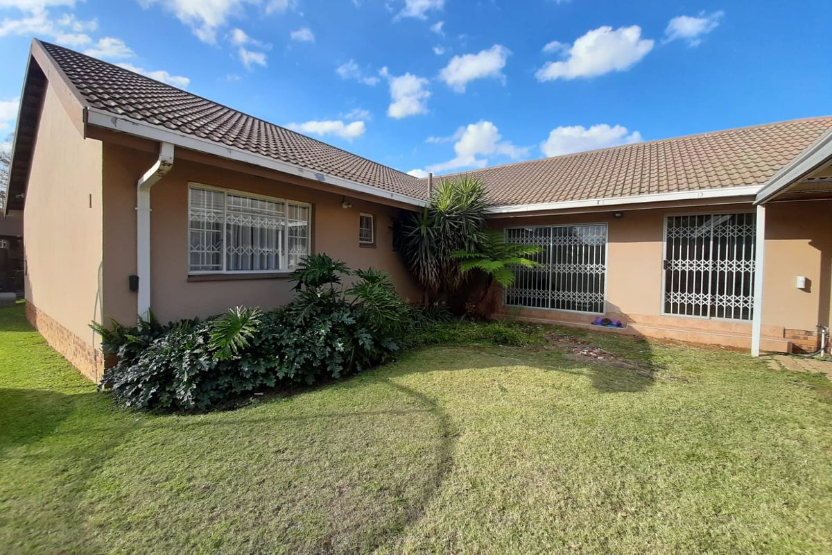 Rear view of the house featuring a tiled roof, security gates on sliding doors, and a private garden area.