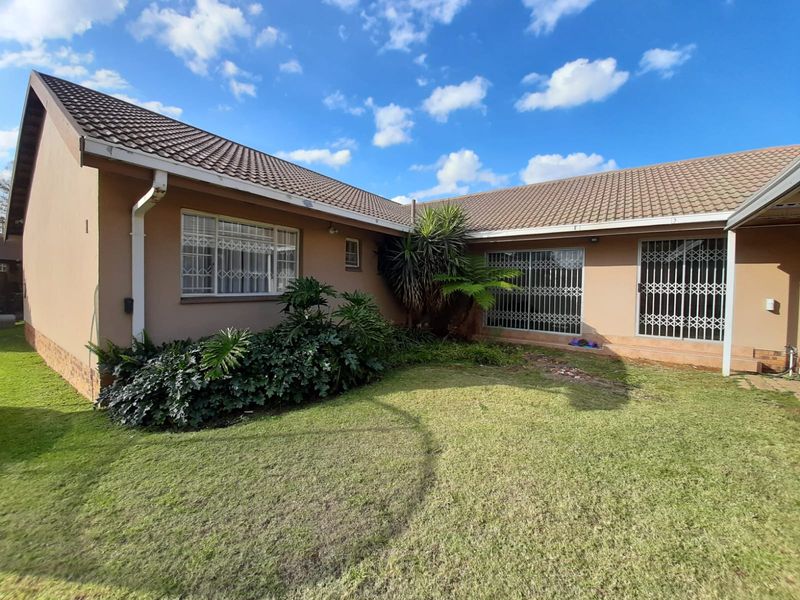 Rear view of the house featuring a tiled roof, security gates on sliding doors, and a private garden area.