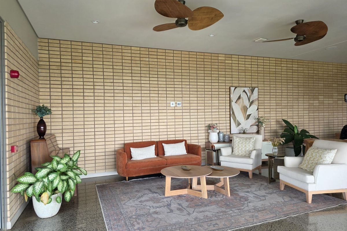 Spacious living area featuring a textured exposed brick feature wall, polished concrete flooring, and dual ceiling fans.