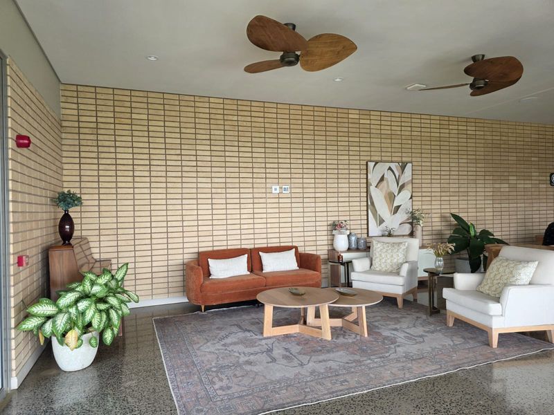 Spacious living area featuring a textured exposed brick feature wall, polished concrete flooring, and dual ceiling fans.