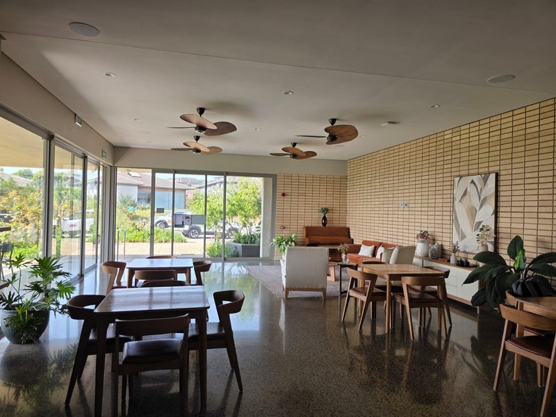 Spacious open-plan living area featuring polished concrete floors, exposed brick feature wall, recessed lighting, and large sliding glass doors opening to the exterior.