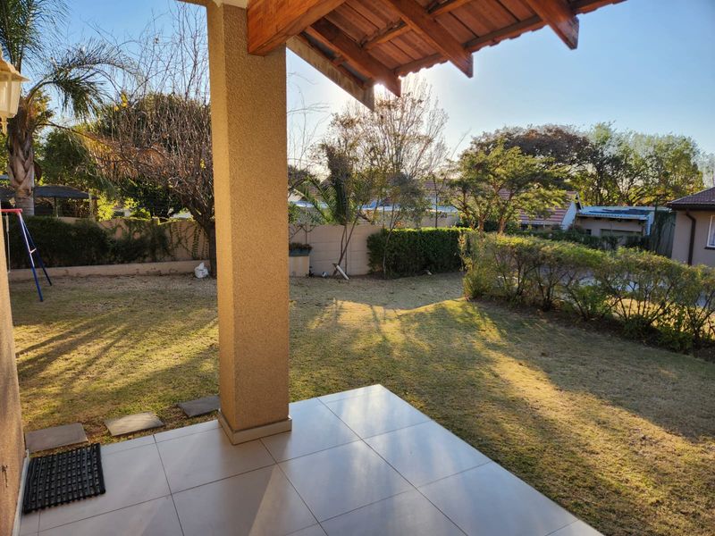 A covered patio area with tiled flooring overlooking a private garden space with boundary walling.