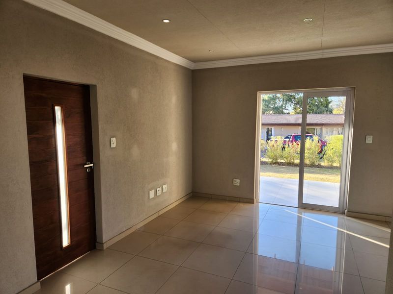 An empty living room featuring tiled floors, recessed lighting, and a sliding glass door providing access to the exterior.