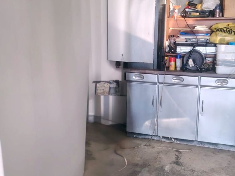 A functional garage space featuring built-in storage cabinetry and concrete flooring, suitable for vehicle parking or workshop use.