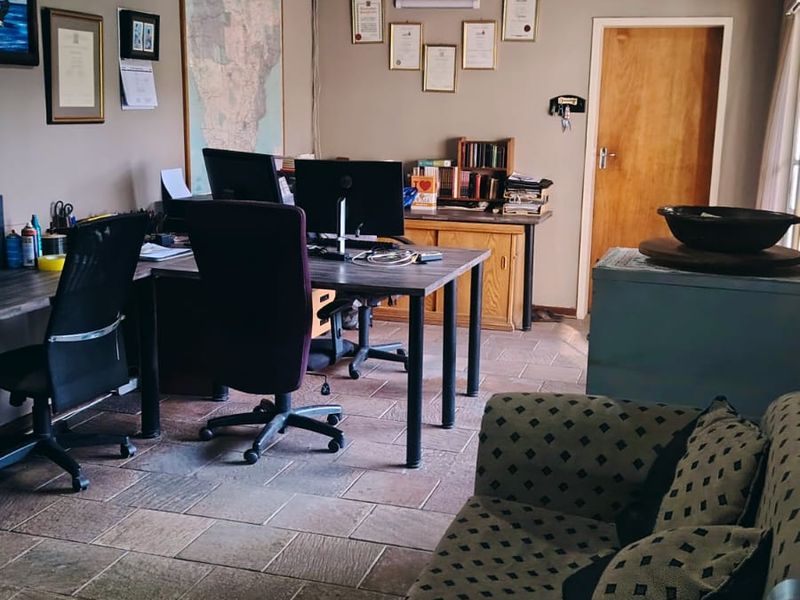 A functional home office space featuring tiled flooring, a timber-paneled ceiling, and a wall-mounted air conditioning unit.