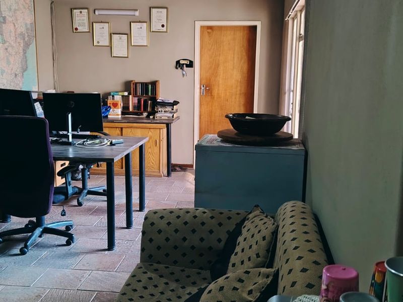 A functional home office space featuring tiled flooring, a timber-clad ceiling, and a wall-mounted air conditioning unit.