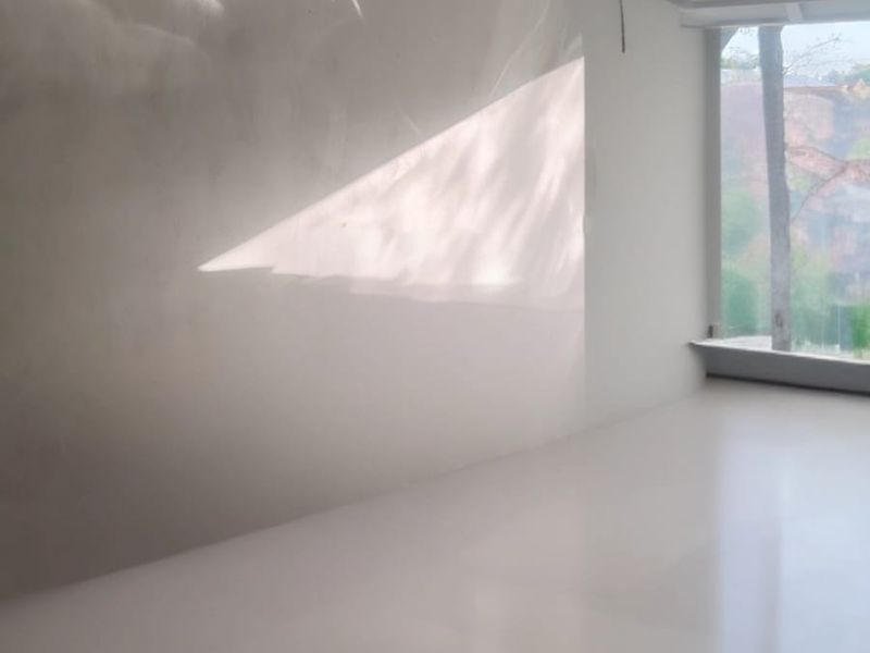 A bright, empty garage space featuring smooth flooring, a large window, and recessed ceiling lighting, offering a clean and versatile area.