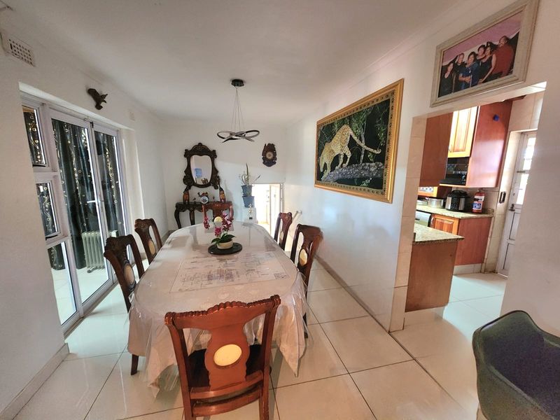 A dining room featuring tiled flooring and sliding glass doors, with an open-plan layout connecting to a functional kitchen area with granite countertops.