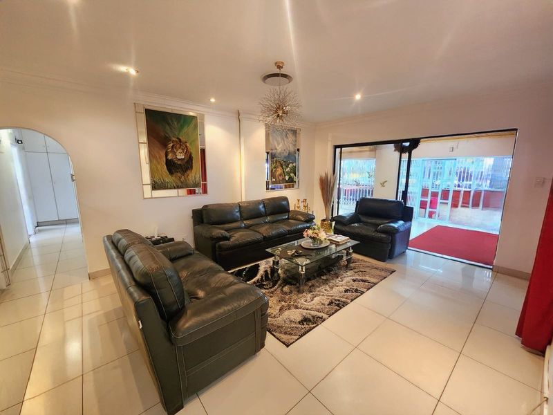 Spacious living room featuring tiled flooring, recessed downlighting, and a large sliding glass door providing access to the outdoor area.