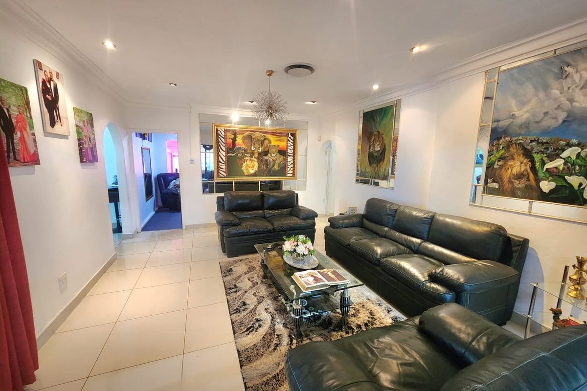 A spacious living room featuring tiled flooring, recessed downlighting, and decorative mirrored wall panels, creating a bright and well-maintained living area.