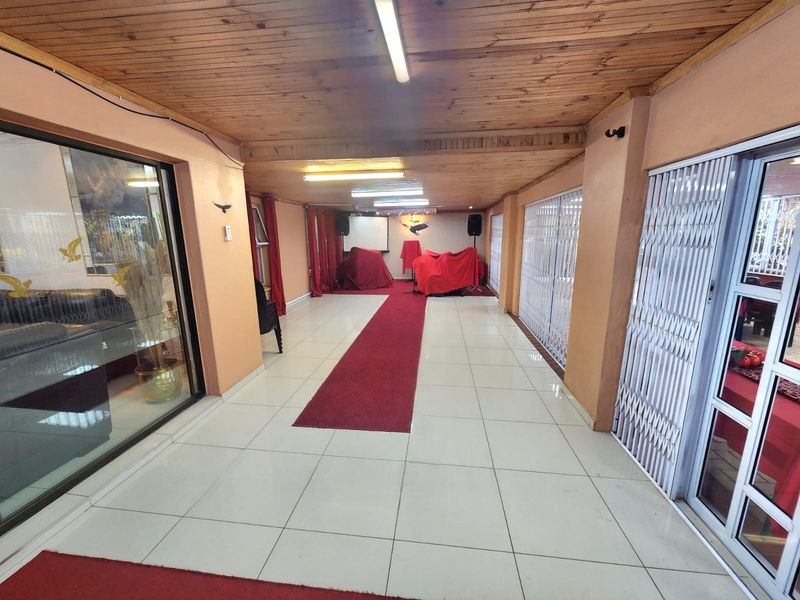 A covered patio area featuring a timber ceiling, tiled flooring, and secure sliding glass doors, currently utilized as a multi-purpose space.