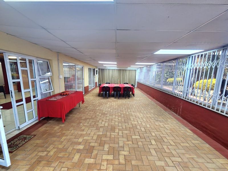 A spacious covered patio area featuring paved flooring, a drop ceiling, and secure sliding door access to the main interior living spaces.