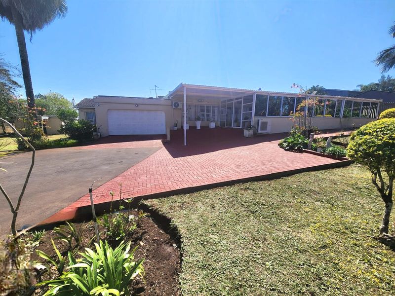 Front exterior view of the house featuring a paved driveway, single garage, and a covered patio area with aluminum-framed windows.