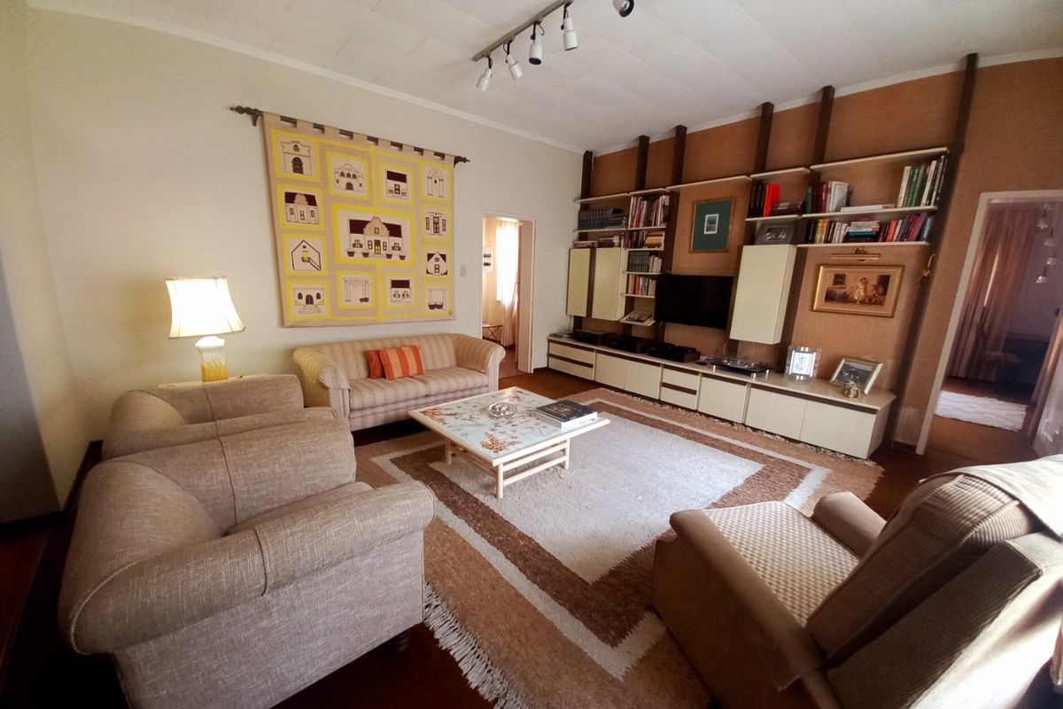 Spacious living room featuring a large built-in wall unit, track lighting, and neutral finishes, offering a comfortable and functional layout.