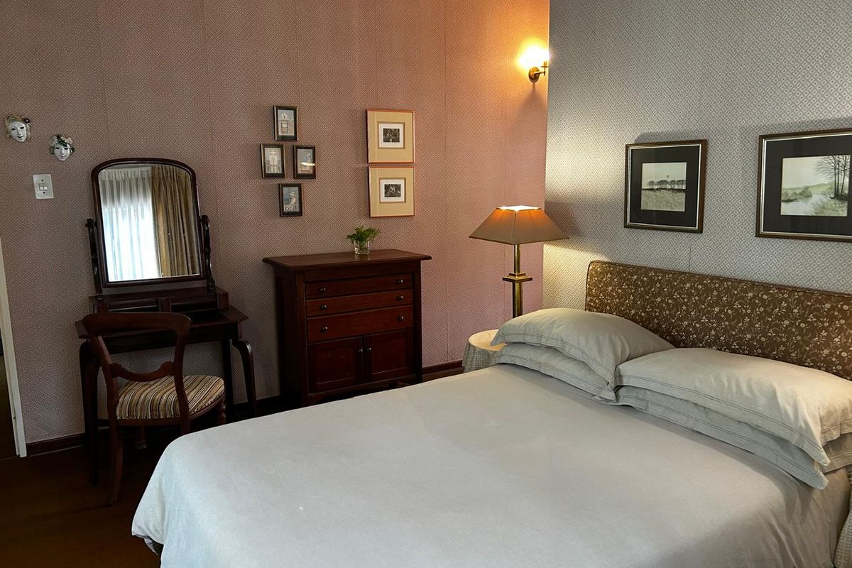 A cozy bedroom featuring patterned wallpaper, a wall-mounted light fixture, and a comfortable bed setup.