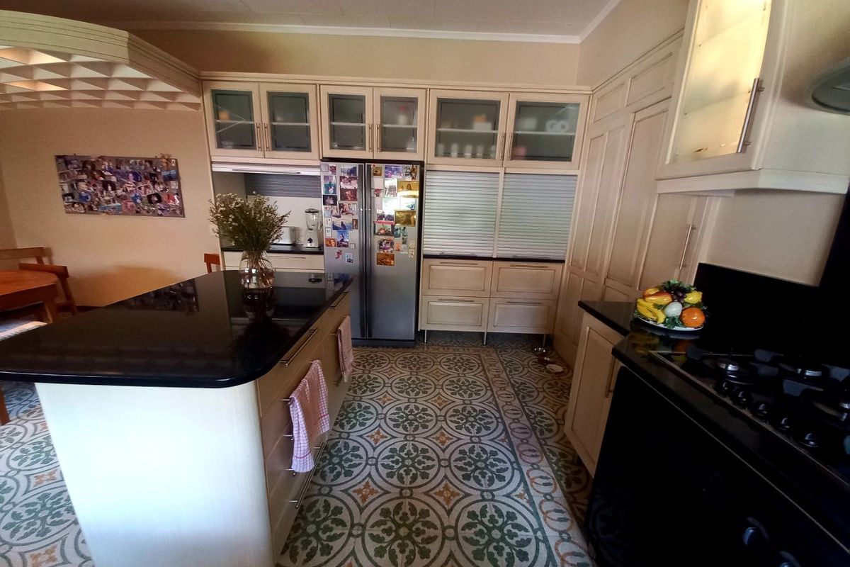 Spacious kitchen featuring a central island with granite countertops, extensive built-in cabinetry, and decorative patterned floor tiles.