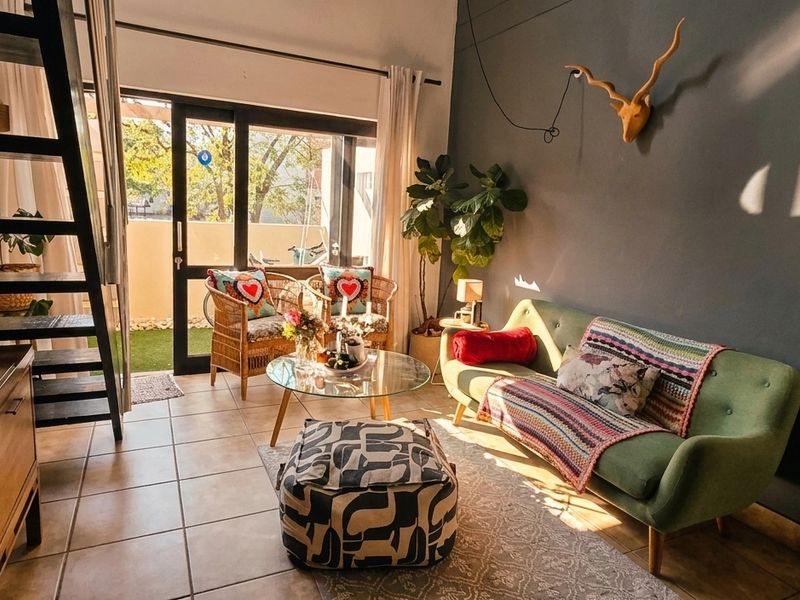 A bright living room featuring tiled flooring, a staircase, and a sliding glass door providing access to an outdoor patio area.