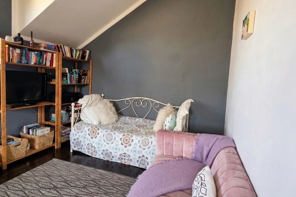 A cozy bedroom featuring a sloped ceiling and dark wood flooring, offering a unique architectural layout.