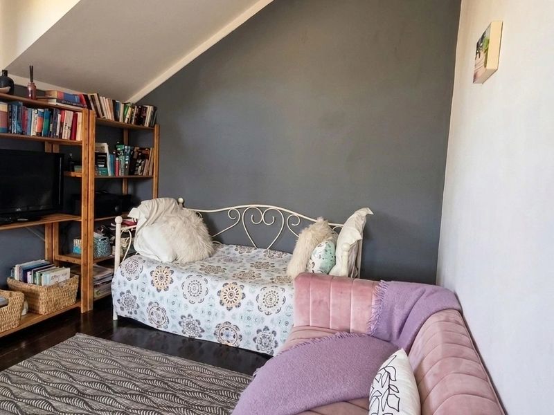 A cozy bedroom featuring a sloped ceiling and dark wood flooring, offering a unique architectural layout.