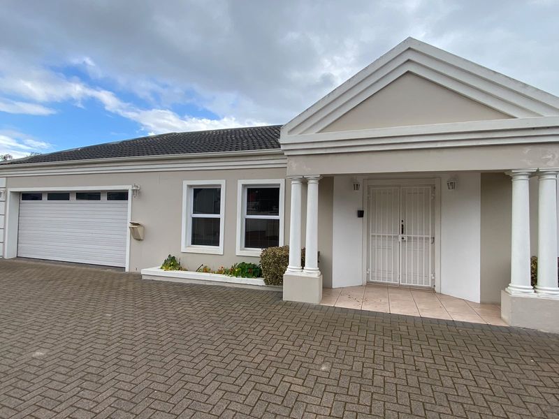 Front elevation of a house featuring a paved driveway, double garage, and a covered entrance porch with classical columns.