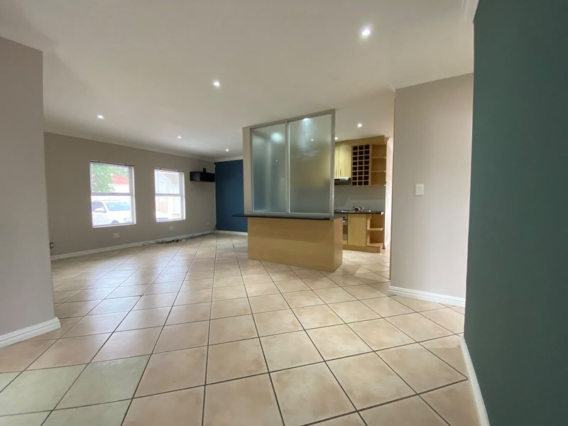 Spacious open-plan living area featuring tiled floors, recessed lighting, and a functional kitchen with built-in cabinetry and a breakfast counter partition.