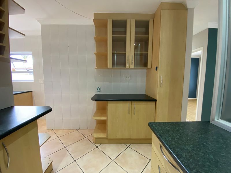 A functional kitchen area featuring light wood-finish cabinetry, dark countertops, and tiled flooring, offering a clean and neutral space ready for personalization.