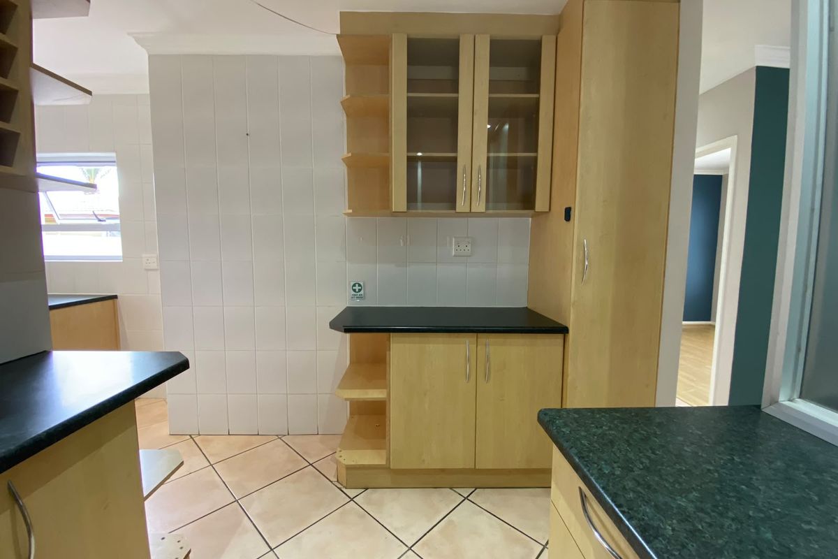 A functional kitchen area featuring light wood-finish cabinetry, dark countertops, and tiled flooring, offering a clean and neutral space ready for personalization.