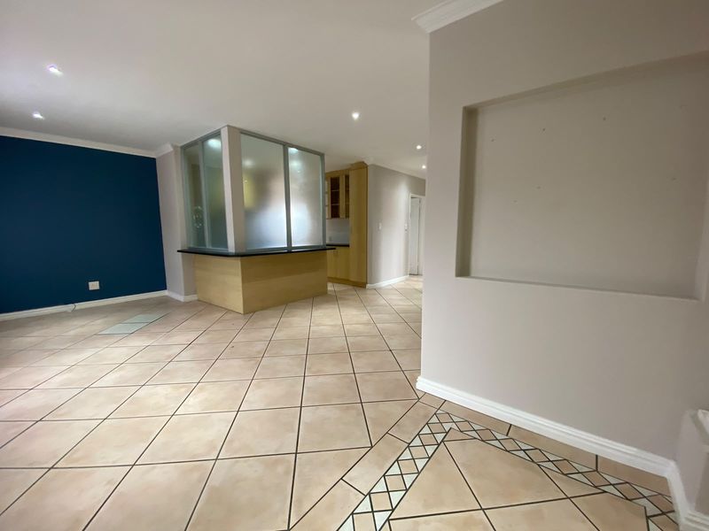 Spacious open-plan living area featuring tiled floors with decorative inlay, a built-in wall niche, and a frosted glass partition separating the kitchen space.