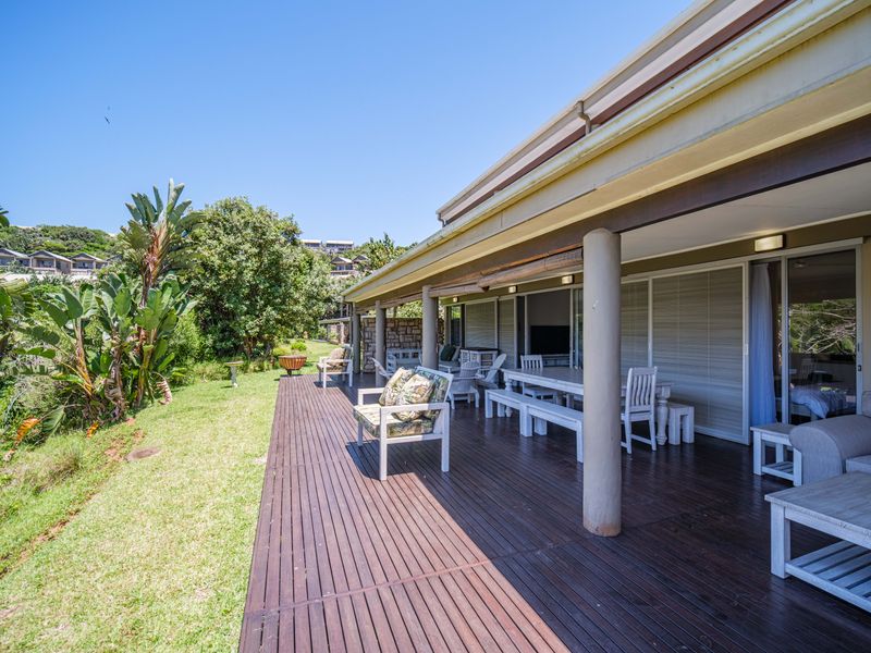 Spacious covered timber deck patio overlooking a lush garden, featuring structural support columns and large sliding glass doors providing seamless indoor-outdoor flow.
