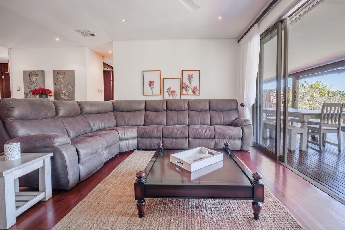 Spacious living room featuring hardwood flooring, recessed downlights, and large sliding glass doors providing seamless access to the outdoor patio area.